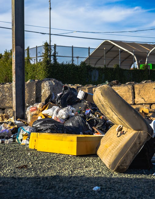 A pile of discarded household and garden rubbish located on a paved driveway in an outdoor setting. The collection includes several large, black bin bags filled with waste, stacked and leaning against
